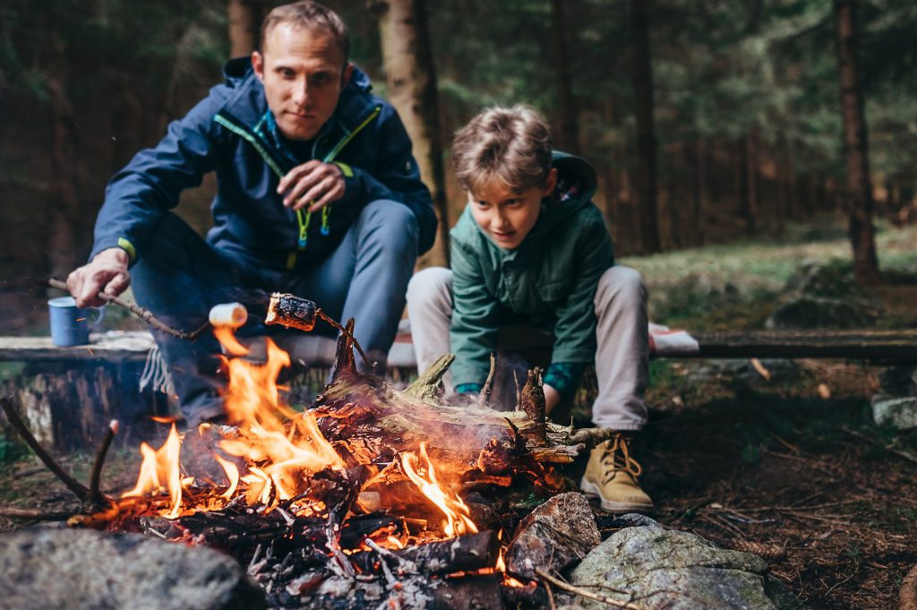 son and dad build campfire